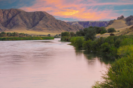 Enjoy the stunning cliffs and winding prairie river. Witness the dramatic hues of the sunset over the wilderness. Immerse yourself in the wild beauty of unspoiled natural landscapes.の写真素材