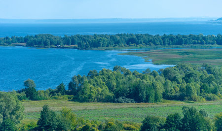 Summer landscape. River in the European part of the world. Sunny warm day. Green trees, grass. Blue sky with a small cloud cover.の写真素材