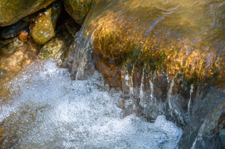 Experience the enchanting dance of a mountain stream. Discover the tranquil solace of nature's embrace. Let the cool waters flow over the ancient rocks. Inviting exploration and wonder.の写真素材