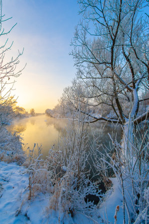 Experience the spectacular beauty of nature's colors at sunrise. Watch the warm sunlight reflect on the icy river. Feel a sense of calm and wonder in the presence of this winter magic.の写真素材