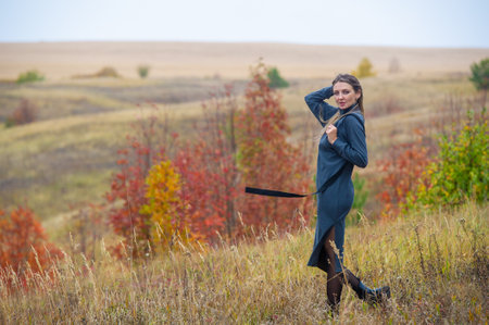 Autumn themed photo shoot with a girl in a warm gray dress. Beautiful colorful trees and hilly landscapes as a background. It visually captures the essence of the fall season in a stunning way.の写真素材