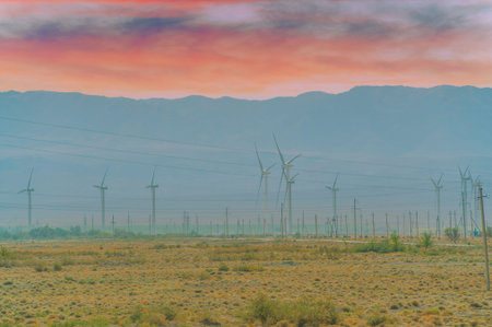 Elegant wind turbines rise against the backdrop of a picturesque sunset. A combination of...