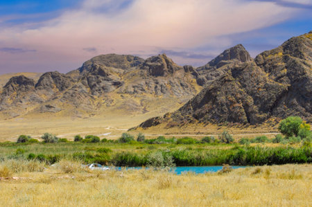 Enjoy the tranquil beauty of the sunset over the calm river. Immerse yourself in majestic mountains and lush green trees. Experience the peace and serenity of nature.の写真素材