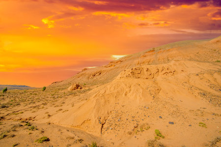 Witness a mesmerizing desert sunset in the Red Boguta Mountains. Experience the golden glow of the sun illuminating the jagged peaks. Be captivated by the beauty of fiery wonders.の写真素材