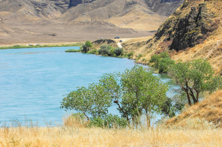 the serenity of the sunset over a calm river. Enjoy breathtaking views of majestic mountains and lush green trees. Feel the beauty of nature and find peace of mind in this stunning place.の写真素材