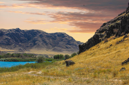 Experience the breathtaking beauty of the steppe. Be enchanted by the tranquil atmosphere of the rocks, river and sunset. Let the serenity of nature reveal your inner peace and awe.の写真素材