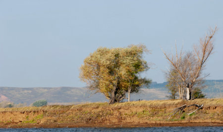 Photo of an autumn landscape, Picturesque autumn landscape of river and bright trees, cloud at the sky.の写真素材