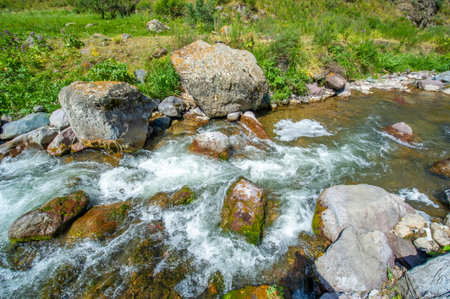 Experience the serene beauty of the river flowing through the rocky canyon. Immerse yourself in the majestic mountains surrounding you. Feel the calm and peace that nature brings to your soul.の写真素材