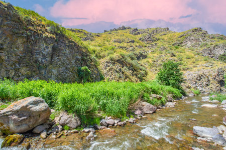 Enjoy the serene beauty of nature in a majestic mountain canyon. Watch the river flow gracefully through the rocky terrain. Immerse yourself in the tranquility of this stunning wonderの写真素材