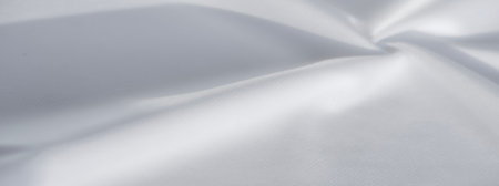 This final white fabric swirl reveals an intricate dance of folds and softness, illuminated by a gentle glow that underscores the textile's airy, serene, and graceful essence.の写真素材