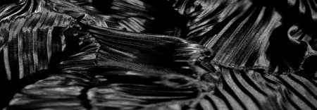 Ripples of midnight fabric delicately curl and unfurl, forming serene, soft echoes of motion. Each gentle ridge cradles embroidered details that quietly twinkle in the monochrome hush.の写真素材