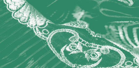 A cascade of pleated green silk adorned with floral lace forms a mesmerizing tapestry of shimmering...
