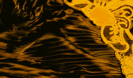Sharp vertical pleats in shimmering gold fabric create a rhythmic pattern that catches the eye. The interplay of dark shadows and bright highlights enhances its sleek allure.の写真素材