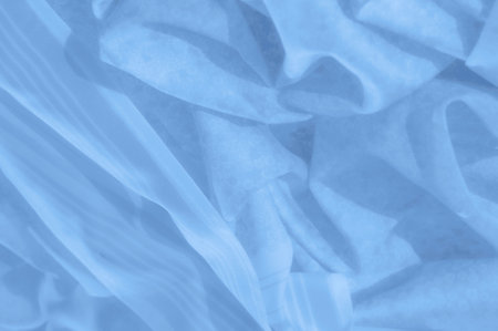 A cascade of soft, blue folds reveals gentle floral silhouettes beneath each layered crease. Wispy patterns flow together, forming a tranquil composition with a light, airy feel.の写真素材