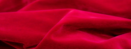 Soft, deep red velvet fabric, elegantly draped to highlight its smooth surface and plush texture. The rich crimson color adds warmth and luxury to any decor or fashion piece.の写真素材