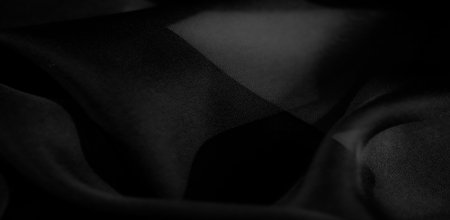 A minimalist depiction of black fabric, accentuating its flowing folds, light-shadow contrasts, and...