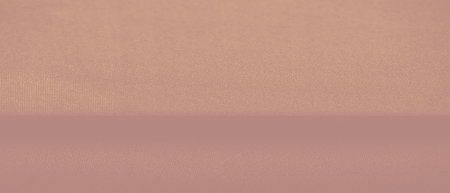 An artistic view of orange fabric showing natural folds and shadow contrasts, creating a soft yet...