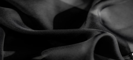 Abstract black fabric close-up, showing soft curves and textures in dramatic lighting. The play of light and shadows highlights the silky surface and delicate folds.の写真素材