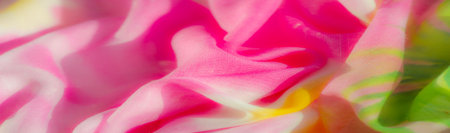 A colorful blend of fabric in pink, yellow, and green hues, captured in a close-up perspective. The soft, rippling folds create a sense of movement, while the semi-sheer quality of the fabric allowsの写真素材