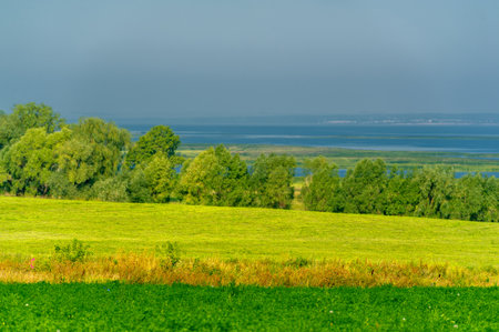 Summer landscape. River in the European part of the world. Sunny warm day. Green trees, grass. Blue sky with a small cloud cover.の写真素材