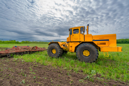 Spring photography, landscape with agricultural machinery, a tractor plows the land, plows a field, birds fly over arable landの写真素材