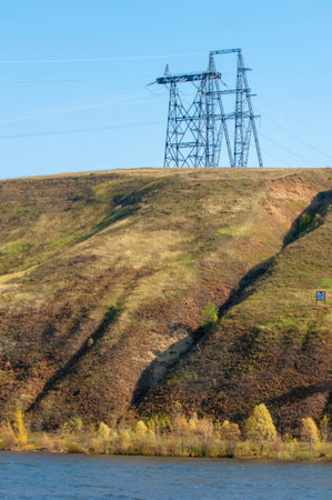 Autumn landscape, river, energy pillars, High voltage pole on blue sky backgroundの写真素材