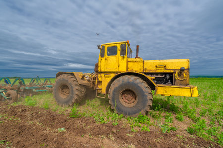 Spring photography, landscape with agricultural machinery, a tractor plows the land, plows a field, birds fly over arable landの写真素材