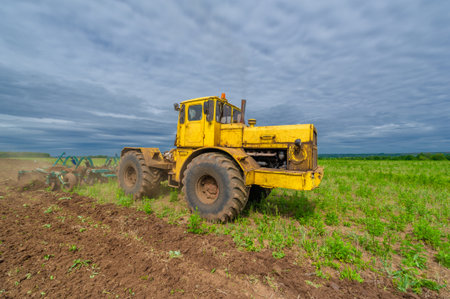 Spring photography, landscape with agricultural machinery, a tractor plows the land, plows a field, birds fly over arable landの写真素材