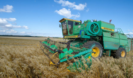 The summer photo of barley harvesting, The modern combine, is a universal machine designed for the...