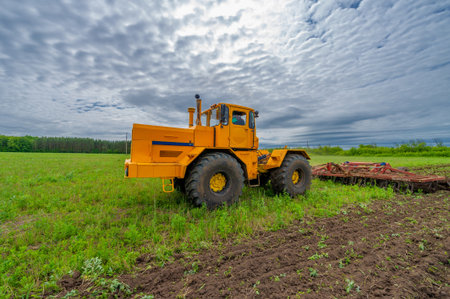 Spring photography, landscape with agricultural machinery, a tractor plows the land, plows a field, birds fly over arable landの写真素材