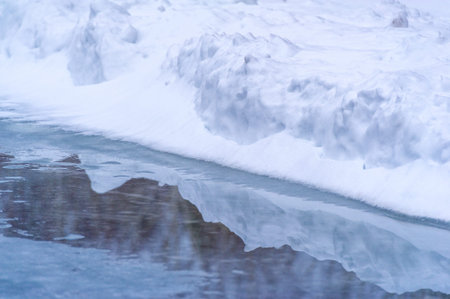 The image showcases a tranquil scene with a reflection of the surrounding environment in the water....