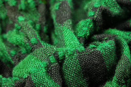 Texture, background, pattern. A woolen scarf to be worn around a person's neck. Green black color on...