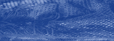 Blur: A textured blue lace fabric with a fine mesh pattern, soft folds, and glowing highlights, offering an artistic portrayal of intricate textile design.の写真素材