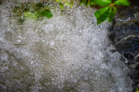 Enjoy the mesmerizing beauty of a mountain stream. Watch the crystal clear water flow gracefully along the stream. Connect with nature and immerse yourself in its serene tranquility.の写真素材