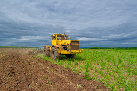 Spring photography, landscape with agricultural machinery, a tractor plows the land, plows a field, birds fly over arable landの写真素材