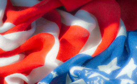 Blur, a patriotic fabric close-up featuring red, white, and blue stripes with stars, resembling the American flag. The image highlights fabric textures, folds, and intricate details.の写真素材