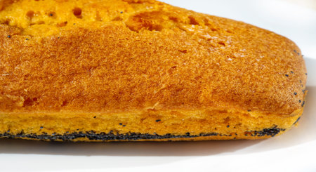 A close-up of a sliced lemon poppy seed cake, revealing its soft, fluffy texture and the contrasting dark poppy seeds. The golden-brown crust surrounds the moist and airy cake,の写真素材