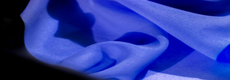 The vibrant blue and black pattern creates a dramatic visual impact. The unique pleating technique adds depth and texture to the fabric. The contrast between the colors is striking.の写真素材