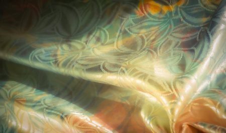 Close-up of shimmering, floral-patterned fabric in golden, orange, and green hues. The intricate...