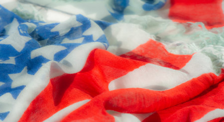 Blur, detailed view of a textured fabric inspired by the American flag, featuring red, white, and blue colors and stars. The folded, soft material adds a sense of movement to the patriotic design.の写真素材