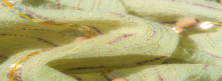 Blurred light green fabric with pink and golden embroidered lines, complemented by shimmering...