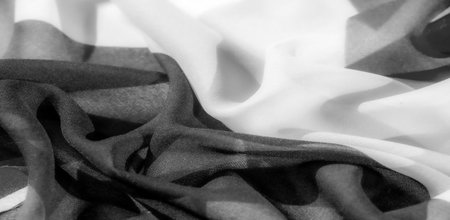 Luxurious fabric with an exquisite silky texture in black and white tones. Its slightly wrinkled texture adds depth and volume to the design.の写真素材