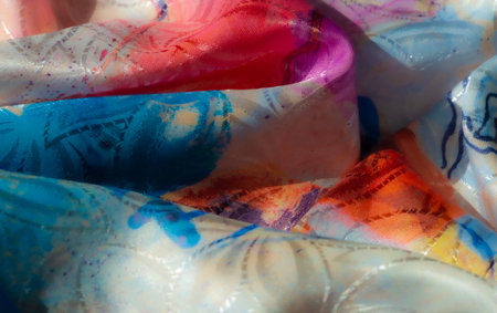 Colorful flowing fabric with swirling patterns of blue, red, and yellow, evoking movement and...
