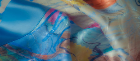 Vibrant fabric with swirling blue, pink, and yellow patterns, capturing the interplay of light on...