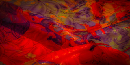 Vivid folds of orange, yellow, and red fabric with purple abstract patterns, highlighted with light...