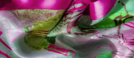 Close-up of bright pink and green abstract fabric, revealing intricate folds and detailed patterns with shimmering light reflections.の写真素材