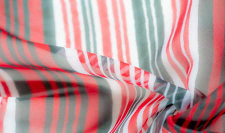 flowing fabric with a vivid stripe pattern in red, black, and white tones. The vibrant colors are enhanced by the soft texture and the delicate interplay of light and shadow,の写真素材