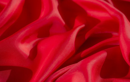 A beautifully detailed macro photograph showing soft red fabric with intricate folds The delicate texture highlights the smoothness and reflective qualities of the material in an abstract arrangemeの写真素材