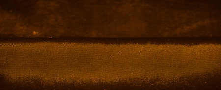 A close-up of a textured surface patterned in warm brown and orange tones. This is silk with a fine repeating grid of small circles creating a uniform, intricate design that feels organic.の写真素材