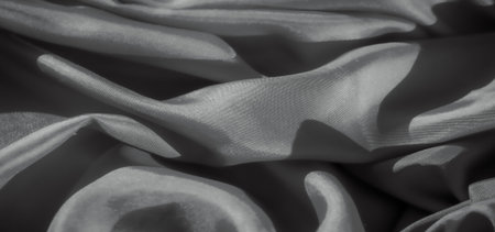 A soft, flowing fabric in monochromatic tones creates a smooth, abstract pattern with subtle highlights and shadows. The intricate folds of the cloth provide texture and depth, making it an elegantの写真素材